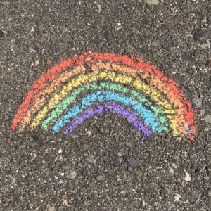 chalk drawing of a rainbow on the pavement, indicative of LGBTQIA issues