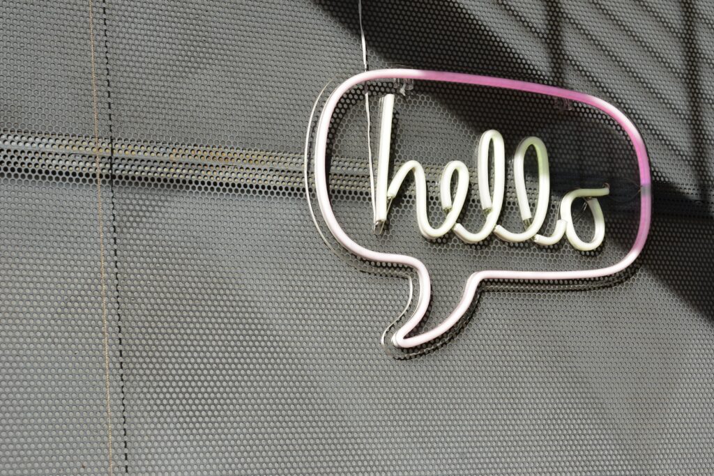Image of a neon sign hanging on a wall that reads "hello" in a speech bubble